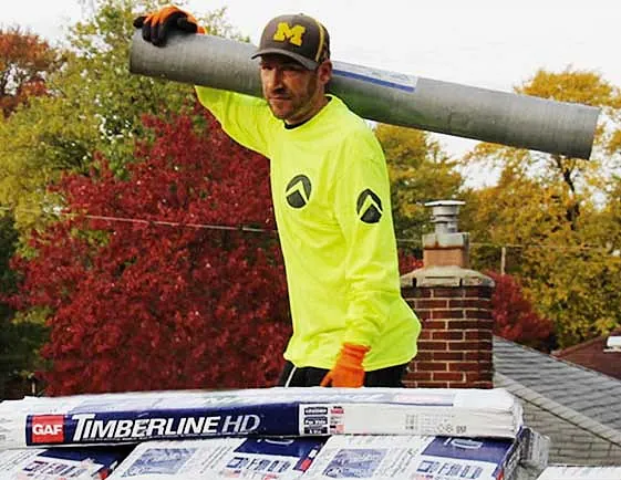 Worker carrying roofing material